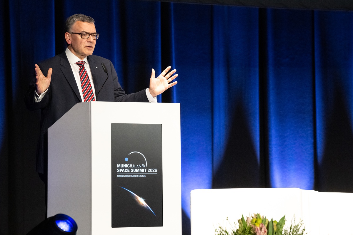  Dr. Florian Herrmann steht an einem Rednerpult und überbringt die Willkommensgrüße der Bayerischen Staatsregierung 