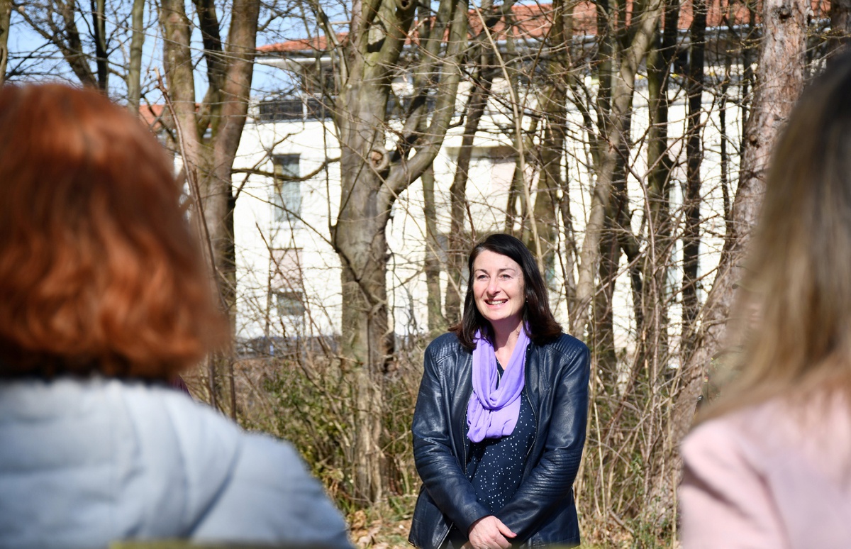 Die zivile Gleichstellungsbeauftragte steht im Freien und spricht zu Menschen.