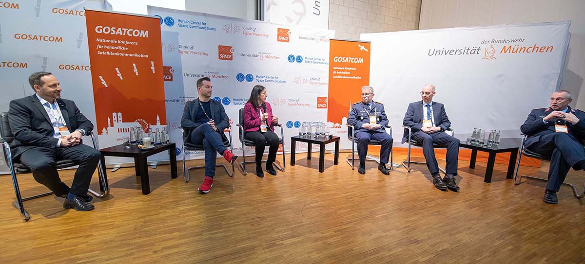 Fünf Männer und eine Frau sitzen auf dem Podium