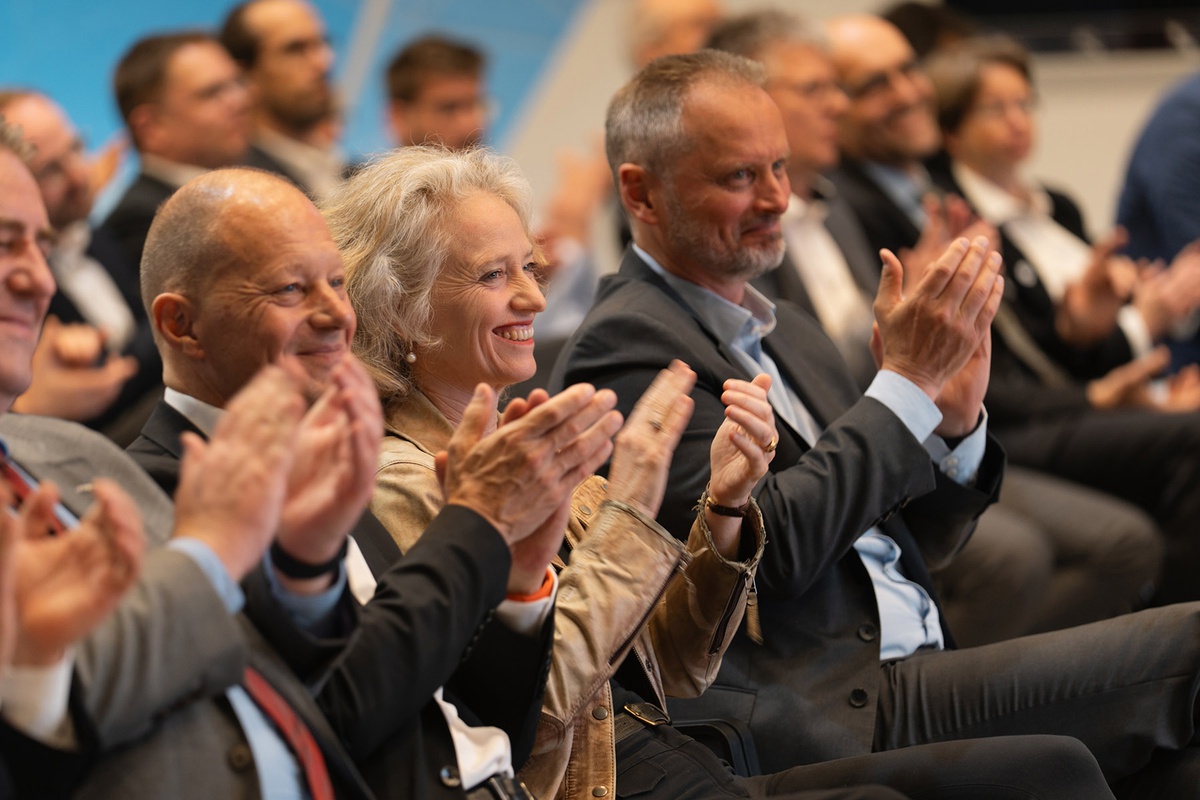 Klatschendes Publikum und im Mittelpunkt sind die Präsidentin der UniBw M Prof. Eva-Maria Kern und der CEO von Airbus Defence and Space Dr. Michael Schöllhorn 