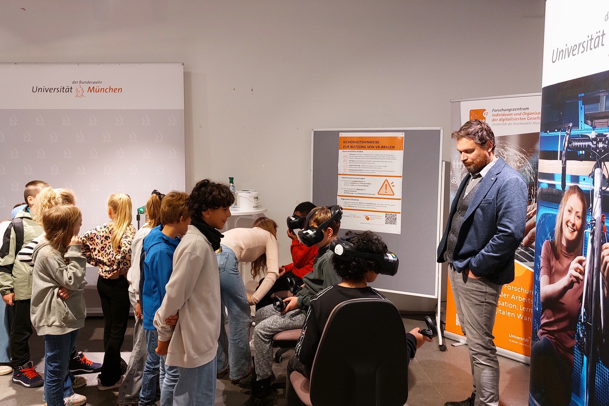 Gruppe von Kindern stehen vor 2 anderen Kindern mit VR-Brillen im Gesicht